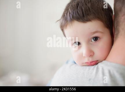 Vater trägt einen traurigen Jungen Stockfoto