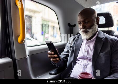 Älterer Passagier, der ein Mobiltelefon auf dem Rücksitz des Taxis verwendet Stockfoto