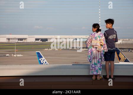 Kinder in traditionellem sommergewichtlichem Kimono, Yukata genannt, beobachten Flugzeuge auf dem Aussichtsterrasse des Haneda International Airport Terminal, Tokio, Japan Stockfoto