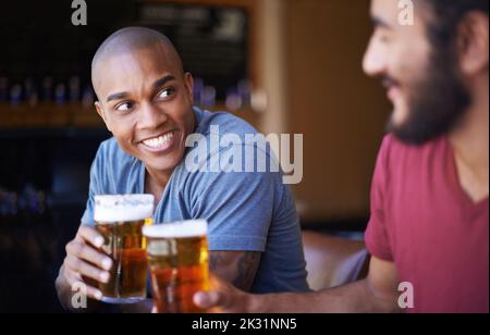 Prost Kumpel. Eine kleine Aufnahme junger Freunde, die in einer Bar einen Drink zu sich nehmen. Stockfoto