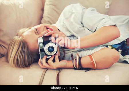 Sagen Sie Käse. Eine schöne junge Frau, die ein Foto auf einer Couch liegend. Stockfoto