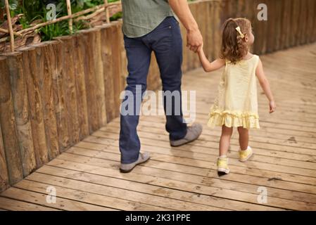 Das Aquarium ist eine große Touristenattraktion. Rückansicht eines Vaters und einer Tochter, die bei einem Ausflug Hand in Hand gehen. Stockfoto