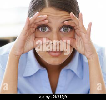 Muss. Bleib. Wach auf.eine junge Frau, die versucht, ihre müden Augen mit ihren Fingern offen zu halten. Stockfoto