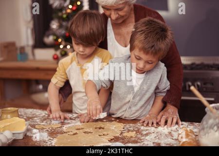 Backtag mit gran...its am besten. Zwei niedliche kleine Jungen backen mit ihrer Großmutter in der Küche. Stockfoto