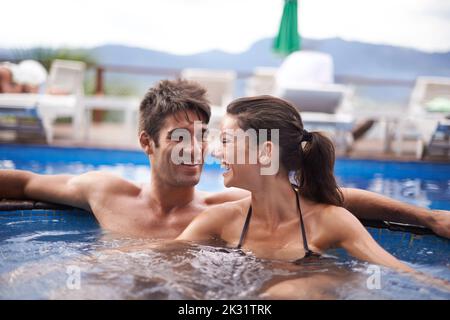 Ein attraktives junges Paar, das sich in einem Pool entspannt. Stockfoto