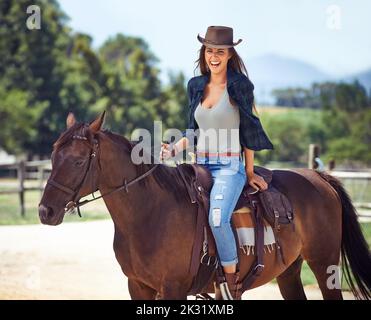 Die Natur lieben. Porträt einer wunderschönen Cowgirl auf ihrem Pferd sitzen. Stockfoto