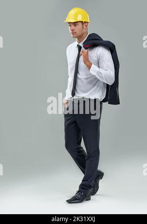 Heute baut man die Welt auf. Studioaufnahme eines jungen Mannes in einem Anzug mit Schutzhelm. Stockfoto