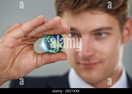 Die Geschäftswelt kann so klein sein... Ein Geschäftsmann, der einen kleinen Globus hält. Stockfoto