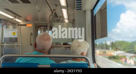 Ein Blick von hinten auf ein älteres Paar, das nebeneinander im Bus sitzt Stockfoto