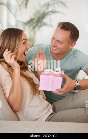 Wow, für mich. Ein hübscher Mann überraschte seine Frau mit einem Geschenk. Stockfoto