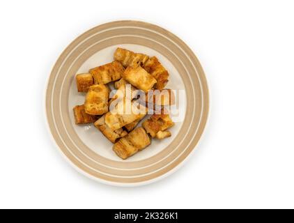 Isolierte Grundpflanze knuspriges Schweinefleisch in einem schönen Gericht auf weißem Hintergrund, Fleisch ohne Nahrung, Draufsicht Bild braune Grundpflanze knuspriges Schweinefleisch. Stockfoto
