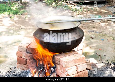 Biryani Kochen in einer Dorfparty auf einem temporären Backsteinofen. Kochen im Freien für viele Menschen in einer großen Aluminiumpfanne mit Holzfeuer. Stockfoto