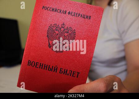 Das Mädchen hält einen von der Russischen Föderation ausgestellten Militärausweis in der Hand. Nahaufnahme, unscharfer Hintergrund. Das Konzept der Mobilisierung. Stockfoto