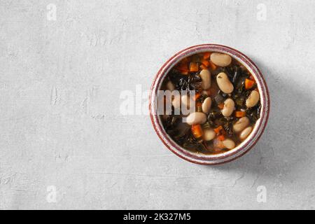 Wintersuppe mit verschiedenen Gemüse, Bohnen, Grünkohl. Typisch toskanische Suppe, Ribollita. Italienisches Komfortessen. Draufsicht, Kopierraum Stockfoto