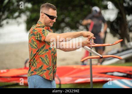 Die Teilnehmer stellen ihre Ausrüstung auf, um beim Waterbourne Watersports Festival, Takapuna, an dem neuseeländischen nationalen Windsurf-Hydrofoil-Rennen teilzunehmen. Stockfoto