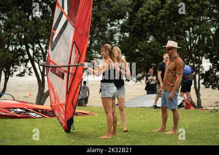 Zwei weibliche Teilnehmer stellen ihre Ausrüstung auf, um beim Waterbourne Watersports Festival am nationalen neuseeländischen Windsurf-Tragflächenboot-Rennen teilzunehmen Stockfoto