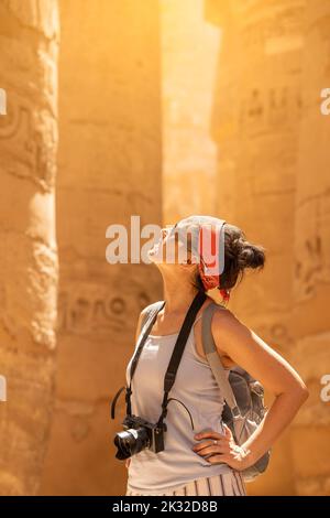 Touristen, die in einem Tempel auf Säulen mit Hieroglyphen blicken Stockfoto