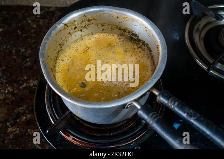 Milchtee-Zubereitung auf einem Gasherd in einer Indian House Hold Kitchen. Tabellenansicht von oben. Uttarakhand indien. Stockfoto