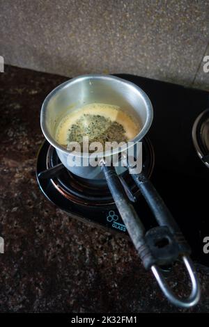 Milchtee-Zubereitung auf einem Gasherd in einer Indian House Hold Kitchen. Tabellenansicht von oben. Uttarakhand indien. Stockfoto