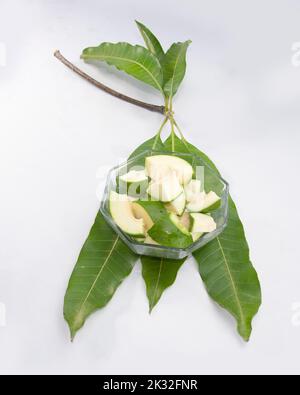 Scheiben roher grüner Mango auf Blättern. Stockfoto