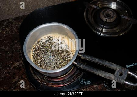 Milchtee-Zubereitung auf einem Gasherd in einer Indian House Hold Kitchen. Tabellenansicht von oben. Uttarakhand indien. Stockfoto