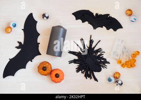 Halloween Feiertagsdekoration mit Kürbissen Papierfledermäuse und Spinnen, Girlande, Süßigkeiten, Süßigkeiten, schwarzen Kerzen auf Holztisch. Halloween-Urlaub im Innenbereich Stockfoto
