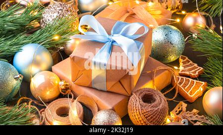 Geschenkboxen mit blauen Bändern, Weihnachtsbaumspielzeug und Kiefernästen. Stockfoto