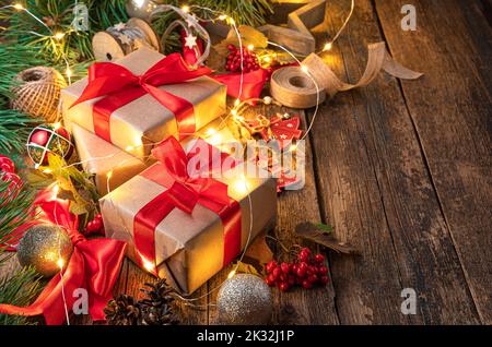 Festlicher Hintergrund mit Geschenken und Weihnachtsbaumspielzeug auf einem Holztisch. Stockfoto