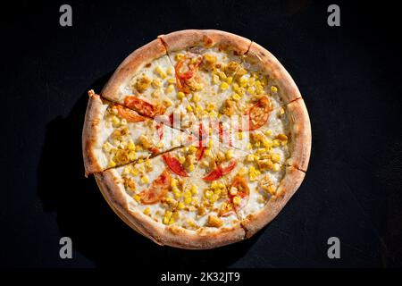 Pizza für Kinder auf Sahnebasis mit Hühnerfilet, Tomaten, Mais und Mozzarella-Käse. Stockfoto