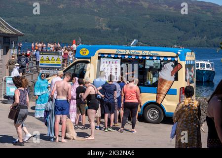 Die Menschen genießen den Sommer in Luss am Loch Lomond, Schottland, beim Springen und Schwimmen im kalten, frischen Wasser des loch. Stockfoto