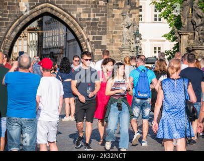 Prag, Tschechische Republik - 2022. Juni: Massen von Touristen, die auf der berühmten Karlsbrücke in Prag spazieren und spazieren gehen. Stockfoto