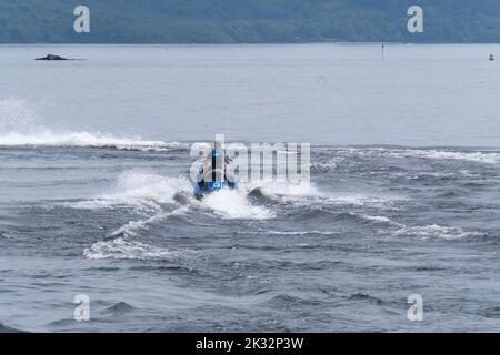 Die Menschen genießen den Sommer in Luss am Loch Lomond, Schottland, beim Springen und Schwimmen im kalten, frischen Wasser des loch. Stockfoto