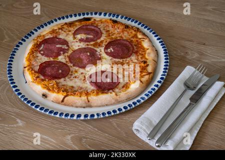 Salami Pizza Italienische Art auf einem runden Teller mit Messer und Gabel Stockfoto