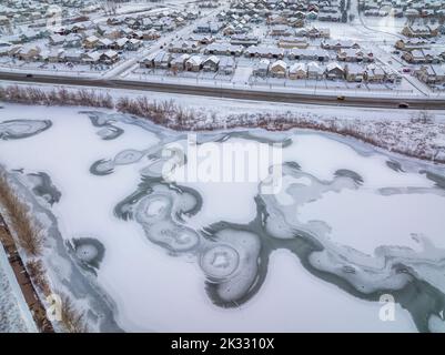 Gefrorener Teich und Wohngebiet in Winterlandschaft nach Sonnenuntergang, Luftaufnahme von Fort Collins im Norden von Colorado Stockfoto