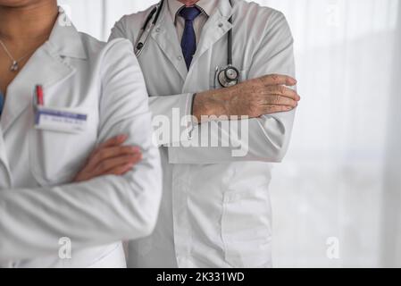 Bild von zwei Kollegen im Krankenhaus, die mit einem Kreuz bewaffnet auf ihre Schicht vorbereitet sind. Stockfoto