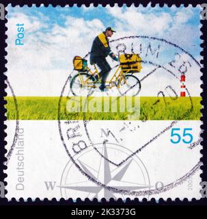 DEUTSCHLAND - UM 2005: Eine in Deutschland gedruckte Briefmarke zeigt Postmann auf Fahrrad, Postarbeiter, um 2005 Stockfoto