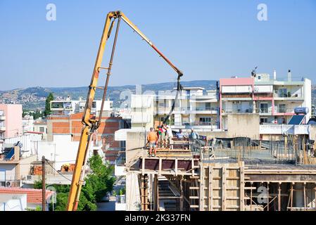 Die Bauarbeiter gießen frischen feuchten Zement auf den Boden des Fundaments eines Wohnungsgebäudes Stockfoto