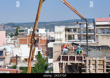 Die Bauarbeiter gießen frischen feuchten Zement auf den Boden des Fundaments eines Wohnungsgebäudes Stockfoto