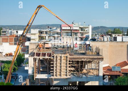 Die Bauarbeiter gießen frischen feuchten Zement auf den Boden des Fundaments eines Wohnungsgebäudes Stockfoto