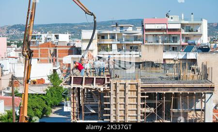 Die Bauarbeiter gießen frischen feuchten Zement auf den Boden des Fundaments eines Wohnungsgebäudes Stockfoto