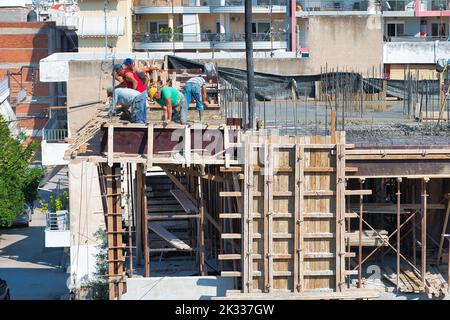 Die Bauarbeiter gießen frischen feuchten Zement auf den Boden des Fundaments eines Wohnungsgebäudes Stockfoto