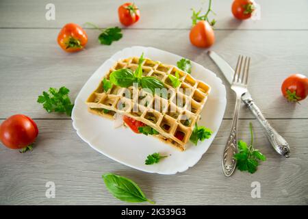 Sandwich aus zwei Eieromeletts mit Speck und Tomaten innen, Waffelform. Stockfoto