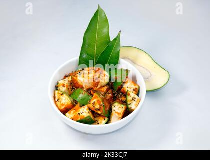 Eine Schüssel mit rohen grünen Mangos mit Pfeffer und Salz und fünf Gewürzen isoliert auf weißem Hintergrund. Stockfoto