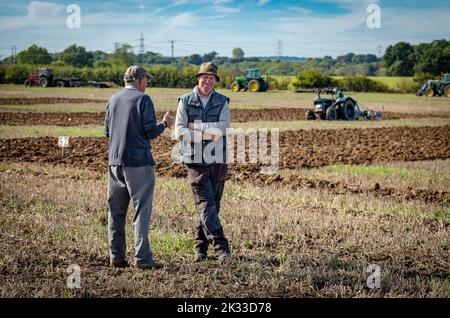 Zwei Richter bei einem traditionellen Feldpflügen-Match plaudern, während die Teilnehmer auf der Oakhurst Farm in der Nähe von Billingshurst das Feld hinter sich pflügen, 24. September 2022. Pflügespiele sind in ländlichen und landwirtschaftlichen Gemeinden in Großbritannien beliebt und finden jeden Herbst nach Abschluss der Ernte statt. Quelle: Andy Soloman/Alamy Live News Stockfoto