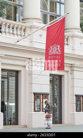 Eine Frau am Telefon vor dem Haupteingang des Royal Opera House (Roh), Bow Street, London, England Stockfoto