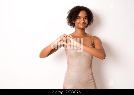 Foto von ziemlich dunkle Haut gewellt Dame macht Herz Figur Symbol mit Händen Kardiologie Schutz Sicherheit tragen elegantes Kleid isoliert weißen Hintergrund Stockfoto