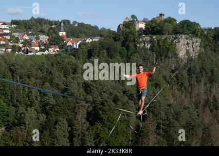 Hohenstein, Deutschland. 24. September 2022. Der Slackline-Läufer Gregor Lawrenz läuft beim Highline- und Familienfest auf einem 360 Meter langen Seil zwischen Schloss Hohnstein und Hockstein in 110 Metern Höhe über das Polenztal. Quelle: Sebastian Kahnert/dpa/Alamy Live News Stockfoto