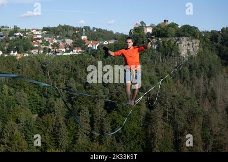 Hohenstein, Deutschland. 24. September 2022. Der Slackline-Läufer Gregor Lawrenz läuft beim Highline- und Familienfest auf einem 360 Meter langen Seil zwischen Schloss Hohnstein und Hockstein in 110 Metern Höhe über das Polenztal. Quelle: Sebastian Kahnert/dpa/Alamy Live News Stockfoto