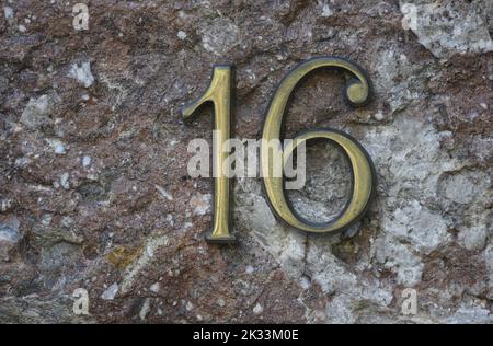 Die Straße aus antikem Messing befindet sich auf einer handgefertigten Steinwand. Stockfoto