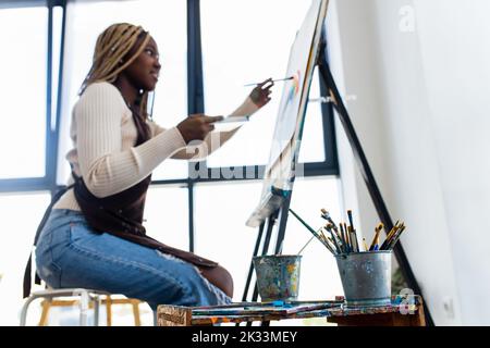 Junge afrikanische Studentin mit Nasenpiercing im Kunststudio Stockfoto